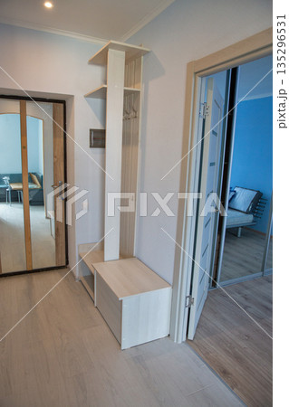 Modern hallway interior with white storage unit and mirror doors. 135296531