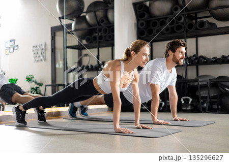 Man and woman exercising together and looking contented and determined Man and woman exercising together and looking contented and determined 135296627
