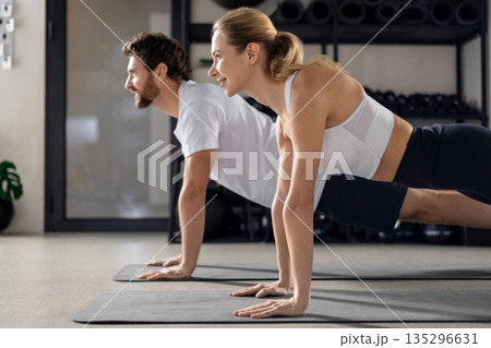 Two people having a workout in gym and standing in plank Two people having a workout in gym and standing in plank 135296631