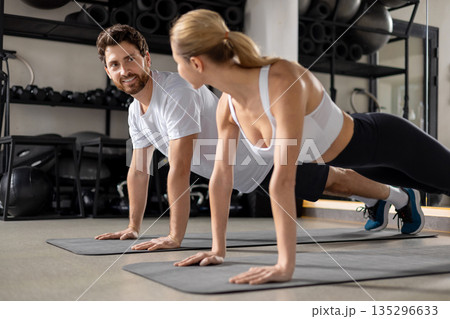 Two people having a workout in gym and standing in plank Two people having a workout in gym and standing in plank 135296633