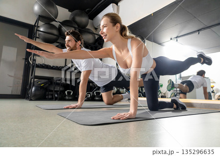 Two young people exercising together and standing in a plank Two young people exercising together and standing in a plank 135296635