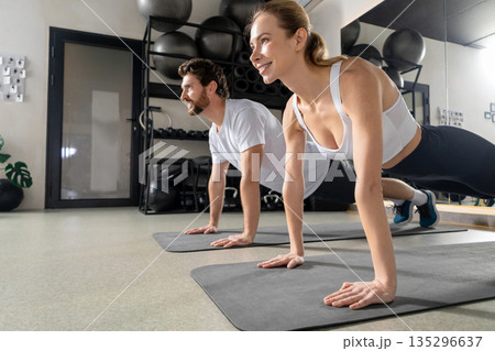 Two young people exercising together and standing in a plank Two young people exercising together and standing in a plank 135296637