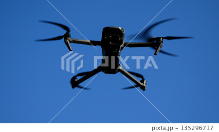 A drone hangs in a blue sky. 135296717