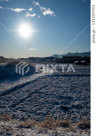 凍て付く冬の朝　薄く雪が積もった農地 135297455