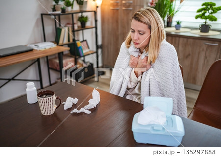 Feeling under the weather while wrapped in a cozy blanket at home Feeling under the weather while wrapped in a cozy blanket at home 135297888