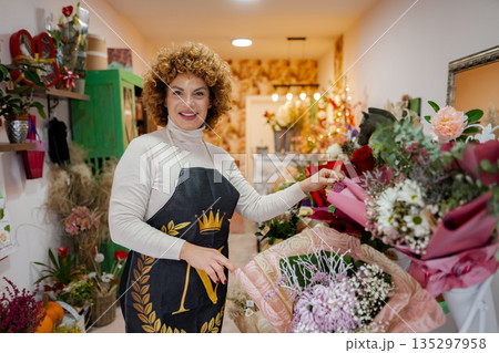 Florist proudly arranging beautiful bouquets in a cozy flower shop 135297958