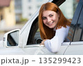 Young woman with red hair driving a car. 135299423