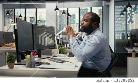 Portfolio manager in office evaluates capital allocation based on statistics and economic indicators. Prop firm expert looks over research reports on screen to drive business growth 135299852