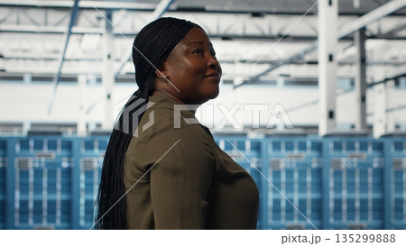 Data center admin conducts security audits to protect against cyber threats and vulnerabilities. Woman walking in server room, ensuring compliance with industry standards, camera B Data center admin conducts security audits to protect against cyber threats and vulnerabilities. Woman walking in server room, ensuring compliance with industry standards, camera B 135299888