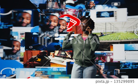 Young woman uses smartphone to do telephone call with mate, discussing online videos. Teenager uses phone to call friend and talk about shared media consumption, colorful multimedia backdrop, camera A Young woman uses smartphone to do telephone call with mate, discussing online videos. Teenager uses phone to call friend and talk about shared media consumption, colorful multimedia backdrop, camera A 135299895