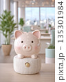 Piggy bank displayed on desk amidst work environment and plants, Scene featuring ceramic coin holder with natural lighting and office background emphasizing budgeting ideals 135301984