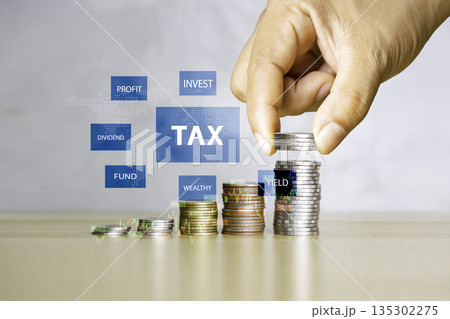 Hand stacking coins with tax, profit, dividend, and yield graphics, symbolizing finance, investment, and wealth management. 135302275