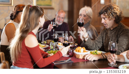Large friendly family gathered at table to have lunch in restaurant 135303219