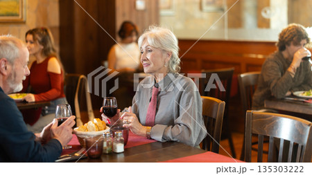 Elderly couple eating and talking in restaurant Elderly couple eating and talking in restaurant 135303222