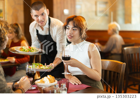 In cafe, guy waiter serves catering establishments couple visitor, puts food on table. 135303223
