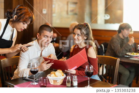 At cafe, Filipino girl waitress communicates with couple of customer, accepts order 135303238