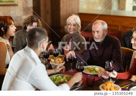 Family members enjoying warm conversation in restaurant 135303249