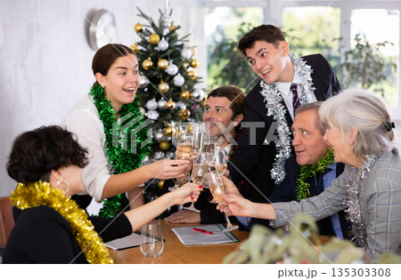 Happy office workers of different ages with tinsels and glasses of champagne enjoying togetner party in meeting room 135303308