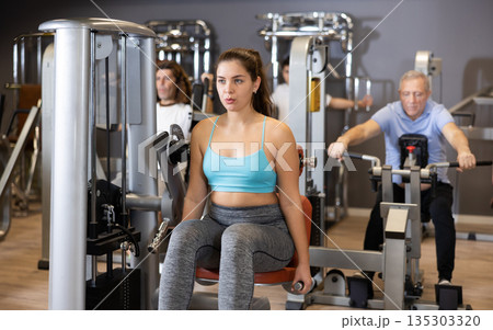 Young girl doing exercises on back extension machine in gym 135303320