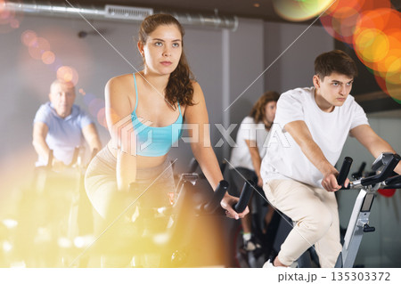 Young girl working out on stationary bicycle in gym 135303372