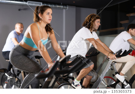 Young girl doing cardio training on stationary bike in gym 135303373