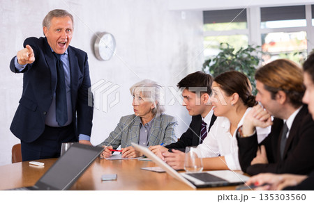 Angry male boss reprehending colleagues on meeting in office Angry male boss reprehending colleagues on meeting in office 135303560