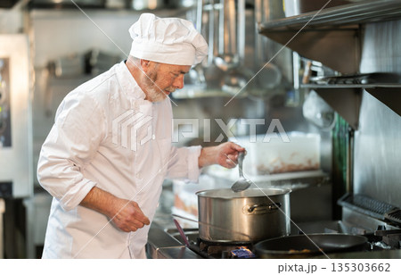 Senior male cook preparing dish in restaurant kitchen 135303662