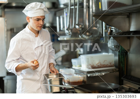 Young male cook preparing dish in restaurant kitchen 135303693