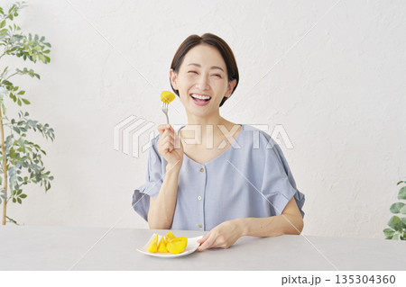 リビングで柿を食べる女性 135304360
