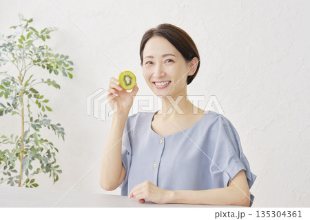 リビングでキウイフルーツを食べる女性 135304361