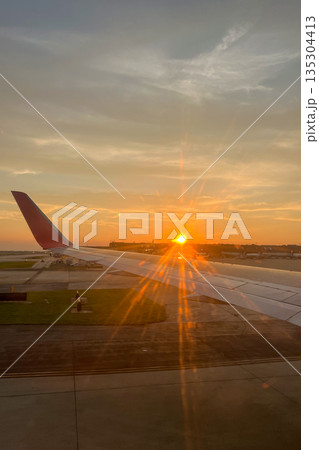 A plane wing is seen in the foreground of a sunset 135304413