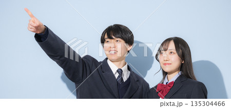 水色背景で並ぶ高校生の男女 女子高生と男子高生の2人の見上げる進路や未来や目標、合格を目指す指を差す 水色背景で並ぶ高校生の男女 女子高生と男子高生の2人の見上げる進路や未来や目標、合格を目指す指を差す 135304466