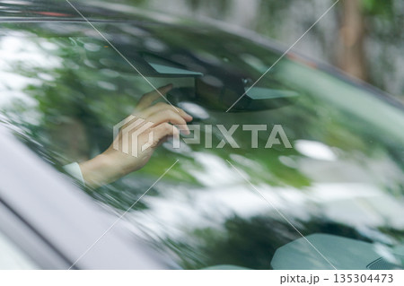 バックミラーを調整するドライバーの手元 135304473