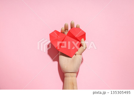 Wooden craft with a red origami heart on pink 135305495