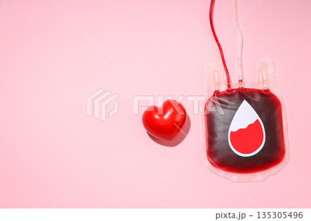 Blood donation bag and a red heart symbol on a pink background 135305496
