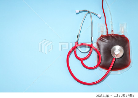 Stethoscope placed next to blood bag on blue surface Stethoscope placed next to blood bag on blue surface 135305498