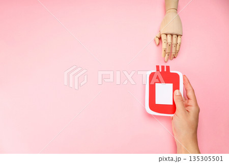 Hand with red blood donation bag on pink background Hand with red blood donation bag on pink background 135305501