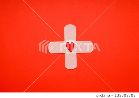 Bandage featuring a heart shape on a red backdrop Bandage featuring a heart shape on a red backdrop 135305505