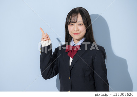 水色背景で女子高生のカメラ目線の上半身の指差しのポイント 水色背景で女子高生のカメラ目線の上半身の指差しのポイント 135305626