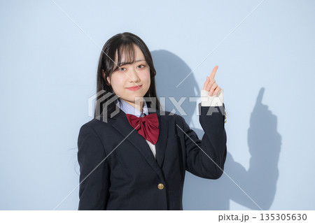 水色背景で女子高生のカメラ目線の上半身の指差しのポイントカメラ目線 水色背景で女子高生のカメラ目線の上半身の指差しのポイントカメラ目線 135305630