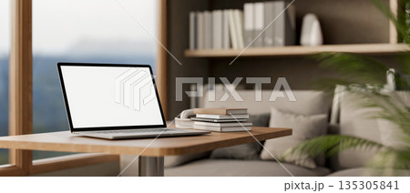 White screen laptop with books on wooden stool table beside fabric sofa in a living room or office. White screen laptop with books on wooden stool table beside fabric sofa in a living room or office. 135305841