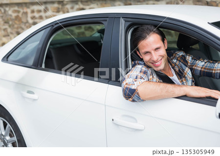 Mid adult man leaning out driver side window, smiling in driveway by white sedan, copy space Mid adult man leaning out driver side window, smiling in driveway by white sedan, copy space 135305949