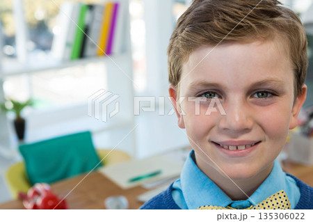 Male child studying in home study area by window with notebook and green pen, copy space 135306022