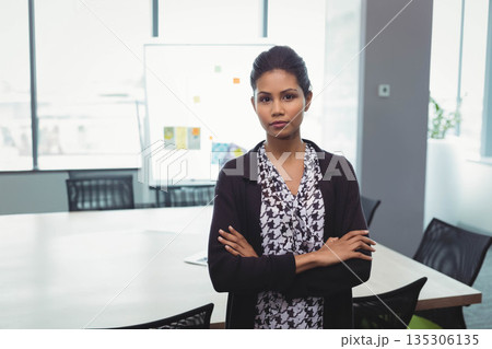 Asian woman in business attire crossing arms in conference room by whiteboard with sticky notes 135306135