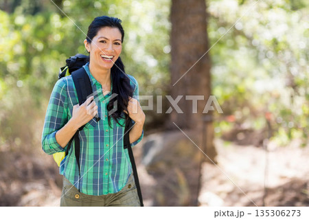 Asian woman standing on wooded trail wearing green shirt with black and yellow backpack, copy space Asian woman standing on wooded trail wearing green shirt with black and yellow backpack, copy space 135306273