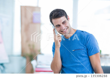 Man holding smartphone and talking on phone at bright office with whiteboard, copy space 135306288