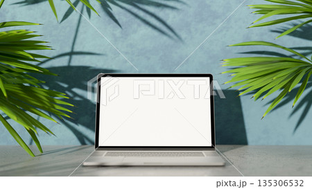 White screen laptop on concrete cement floor in front of a blue paint wall and green leaf palm trees 135306532