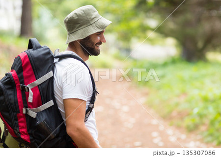 Adult male hiker standing on dirt trail with large red black backpack, bucket hat, copy space Adult male hiker standing on dirt trail with large red black backpack, bucket hat, copy space 135307086