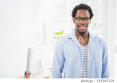 African American man working on computer at office workspace with pencil cup and plant, copy space 135307124