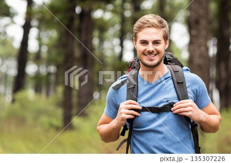Male hiker holding chest strap of large backpack in pine forest clearing, copy space Male hiker holding chest strap of large backpack in pine forest clearing, copy space 135307226